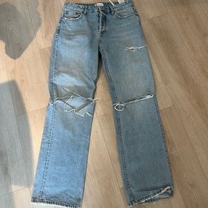 Blue light Zara jeans with holes at the knee level.
